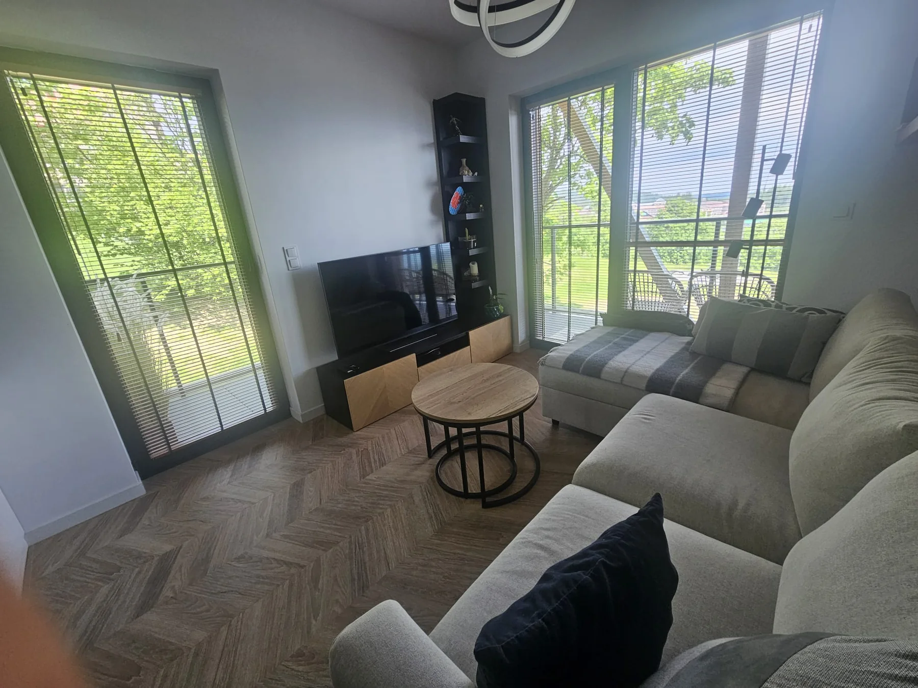 Jasny salon apartamentu z dużymi oknami i wyjściem na balkon